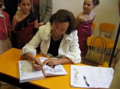Paní Livia podepisuje školní kroniku a&nbsp;také památníčky dětem.